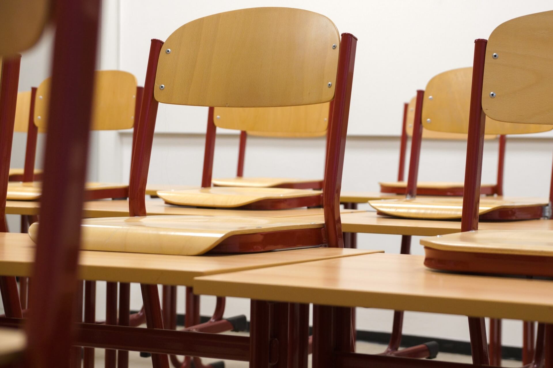 Empty classroom with chairs stacked on desks.
