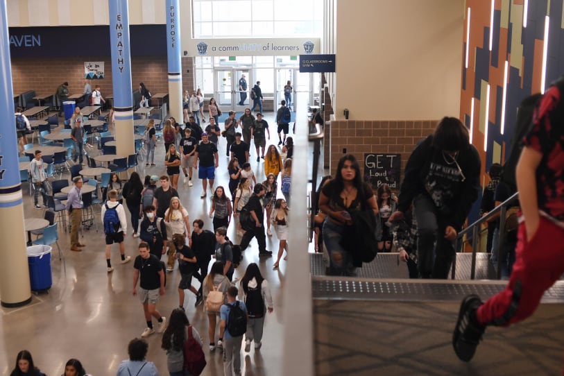 High school students walk up stairs in a hallway during a passing period between classes.