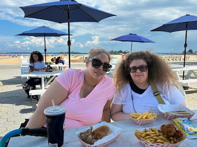 Two females by the beachside are having a burger and fries.