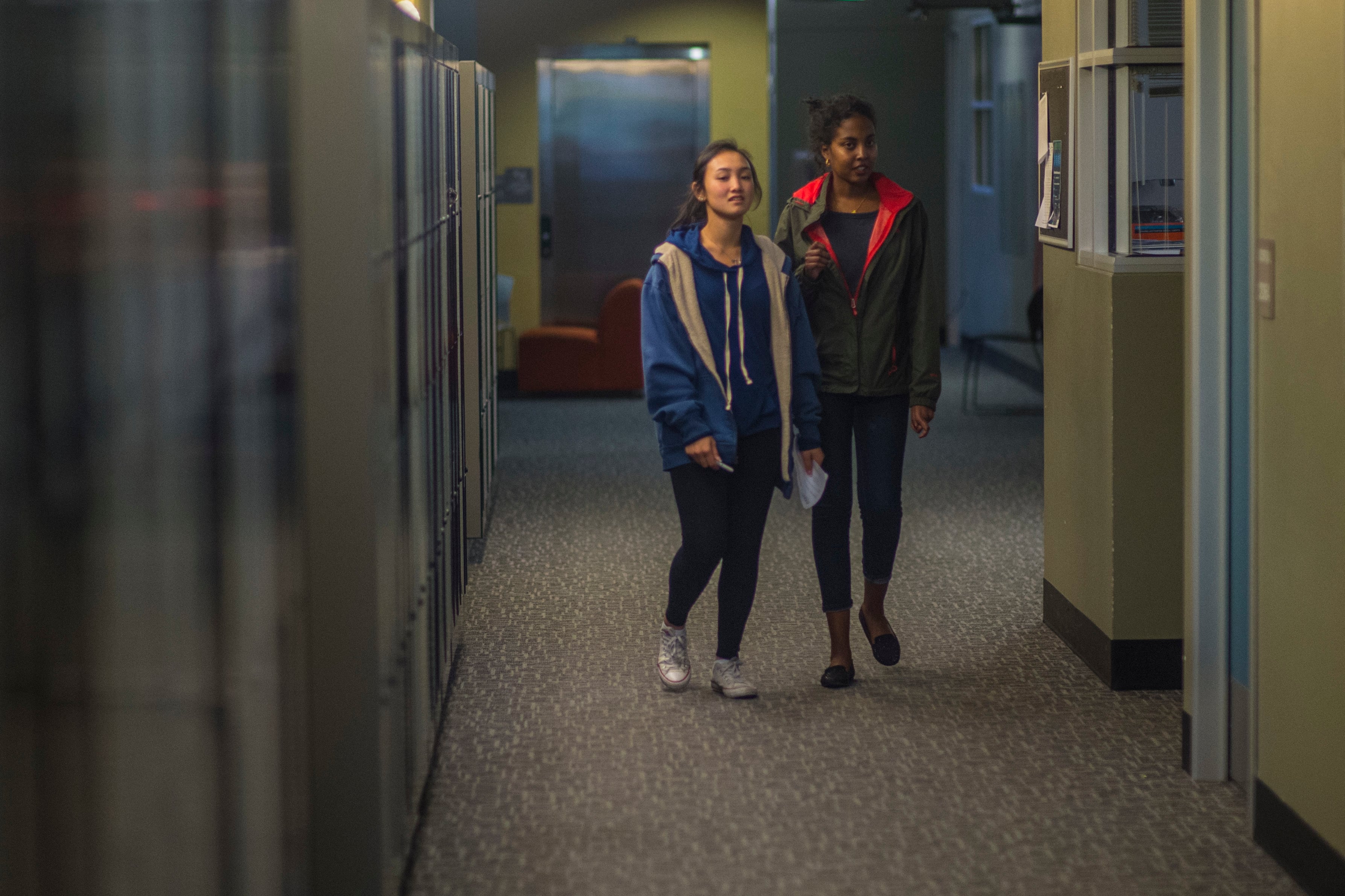 Two high school students walking in a hallway.