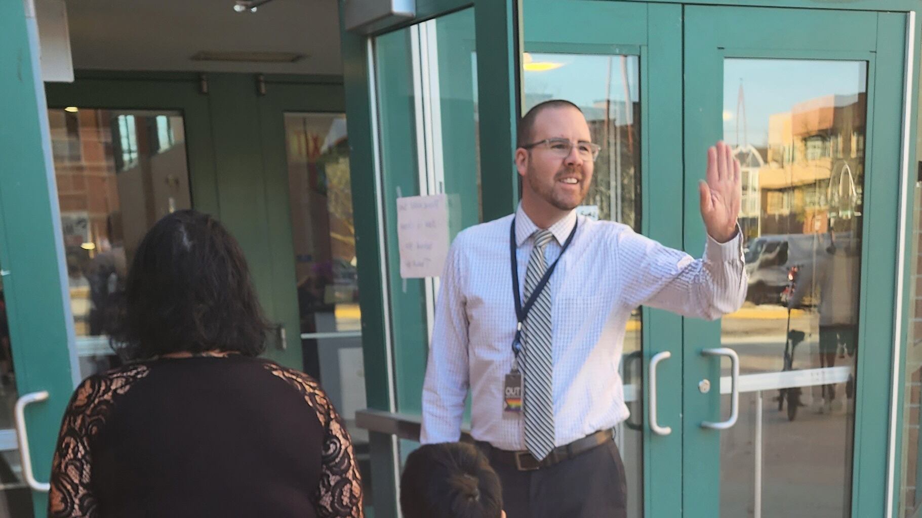 Man waves in front of open door at a Chicago school