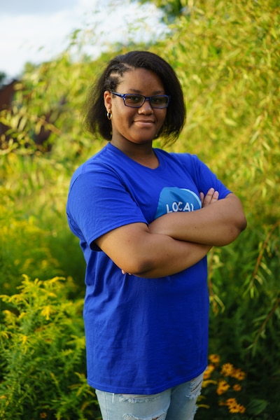 A student stands with her arms folded across her chest.