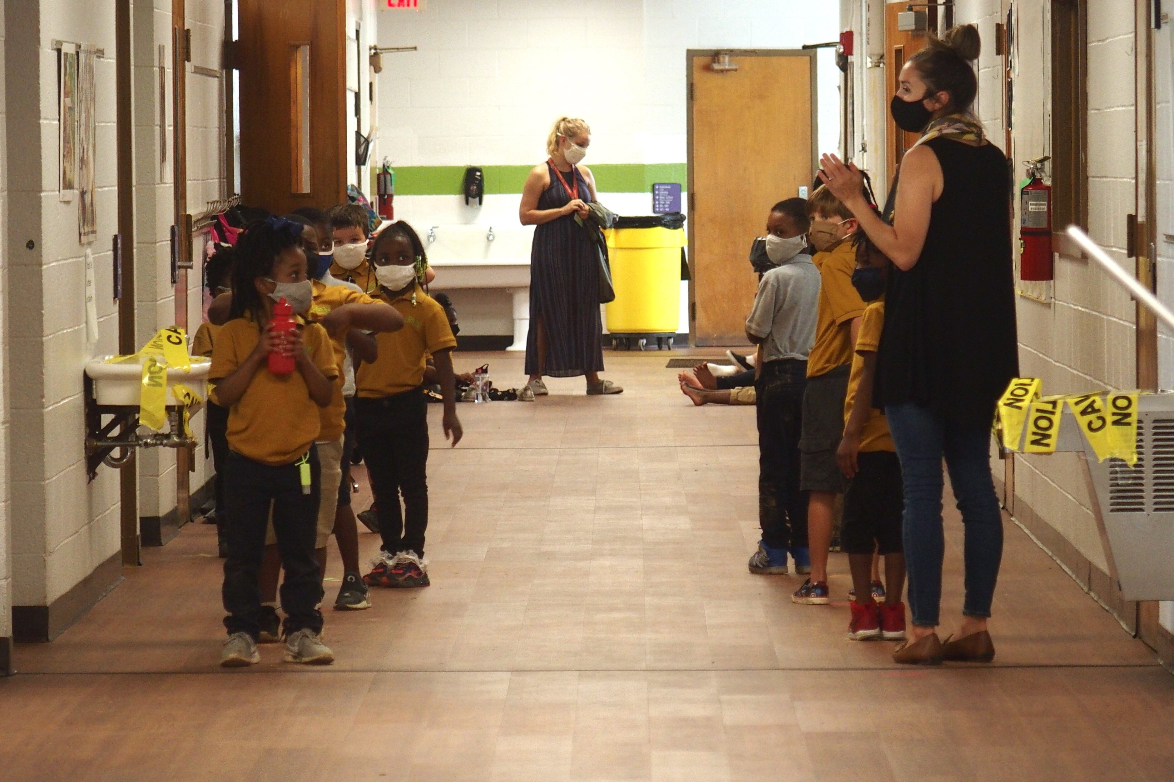 Elementary school students stand in two lines in a hallway