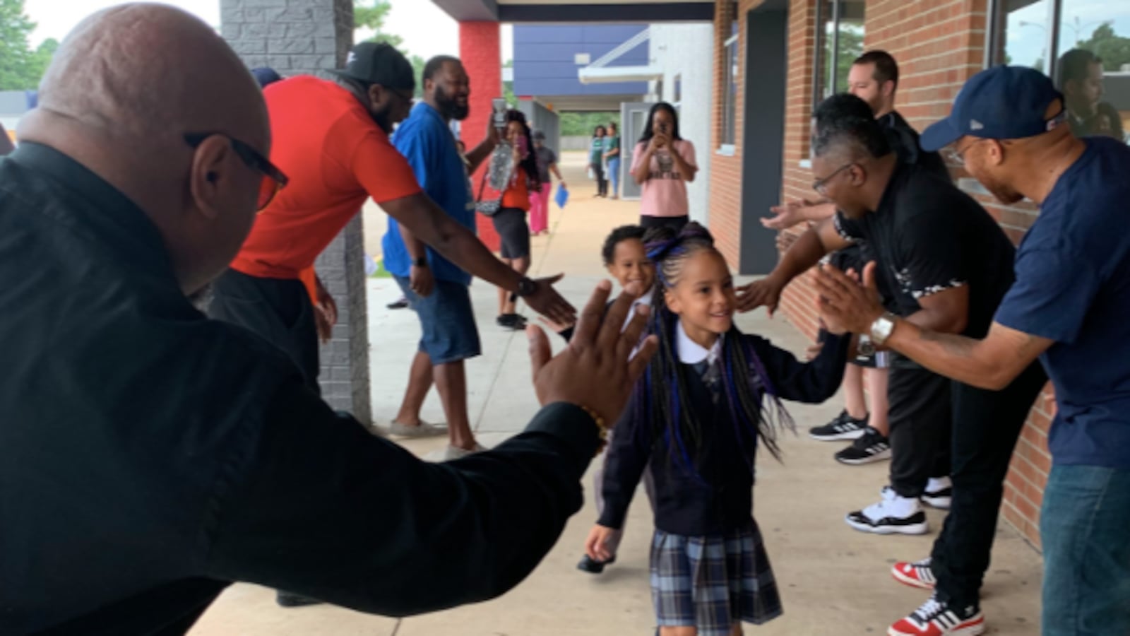 Community members in the Hickory Hill neighborhood offer cheers and high-fives to welcome students back to Power Center Academy Elementary School.