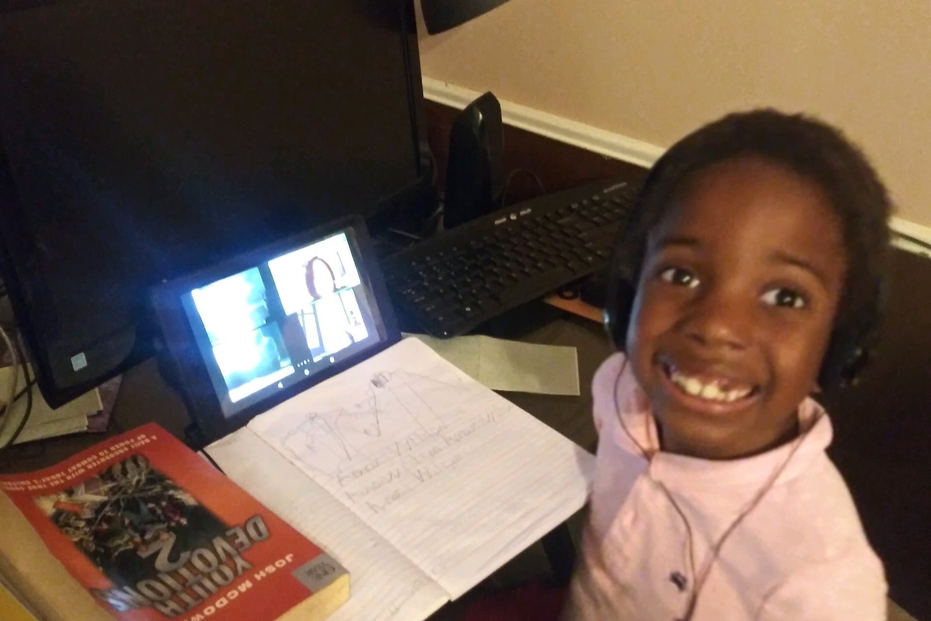 Six-year-old child practices writing his name with his teacher via video conference