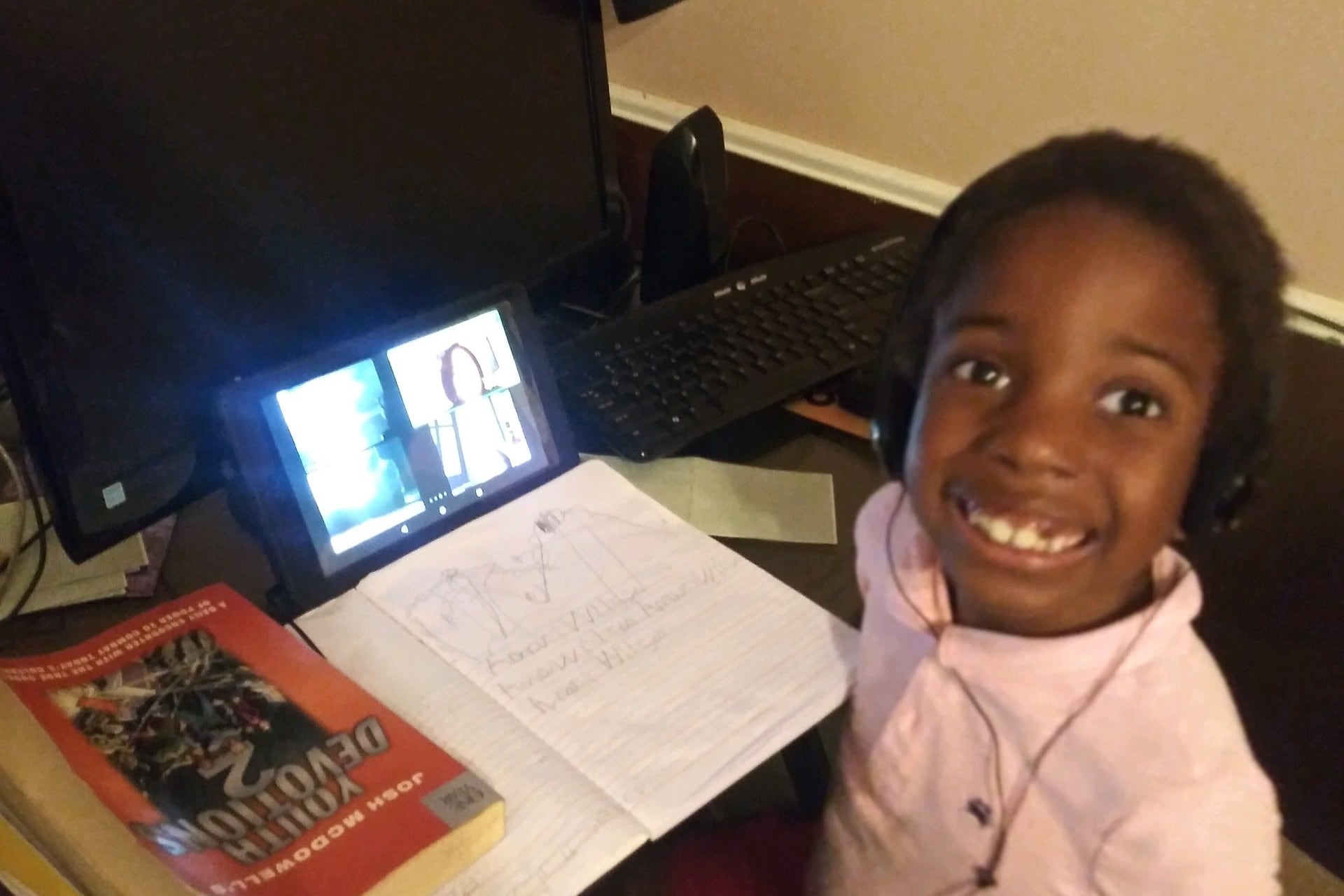 Six-year-old child practices writing his name with his teacher via video conference