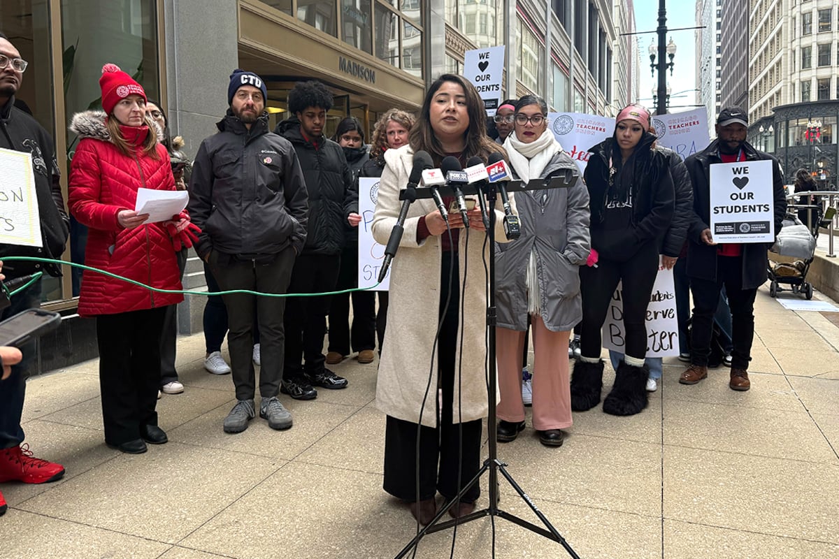 A woman in a white coat speaks at a microphone.