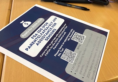 A blue and white flyer with information on it sits on a wooden desk.