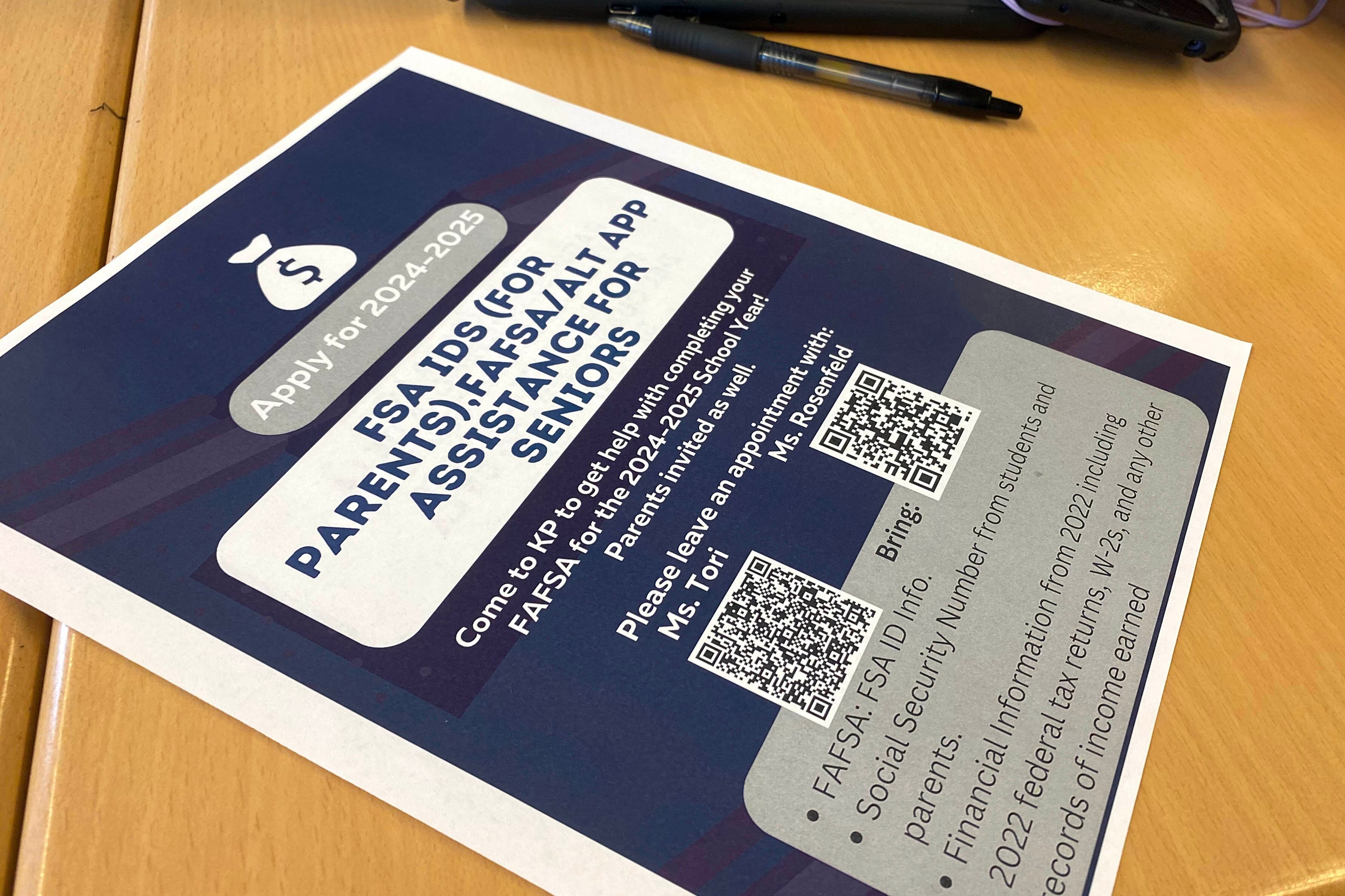 A blue and white flyer with information on it sits on a wooden desk.