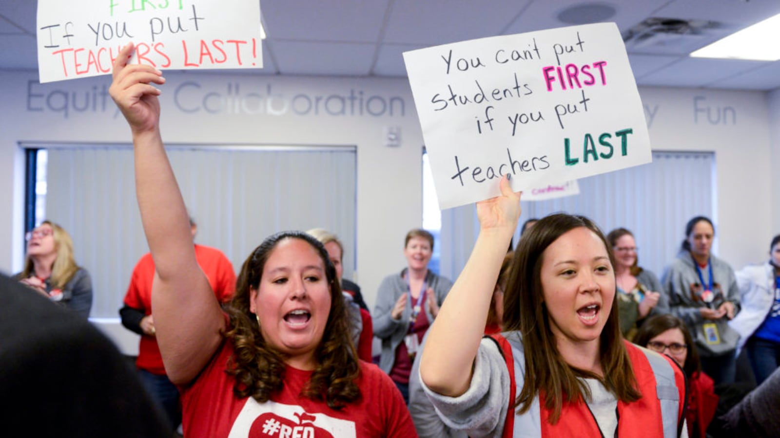 Eagleton Elementary School first grade teacher Valerie Lovato, left, and East High School French teacher Tiffany Choi hold up signs as the Denver teachers union negotiates with district officials.