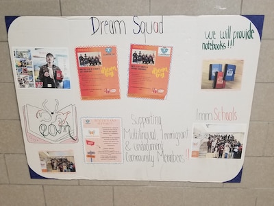 A poster made by a high school student taped to a white brick wall.