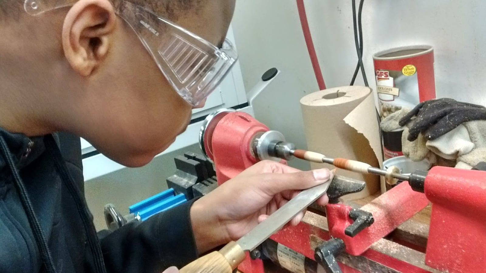 A student wearing goggles works on a piece of heavy machinery.