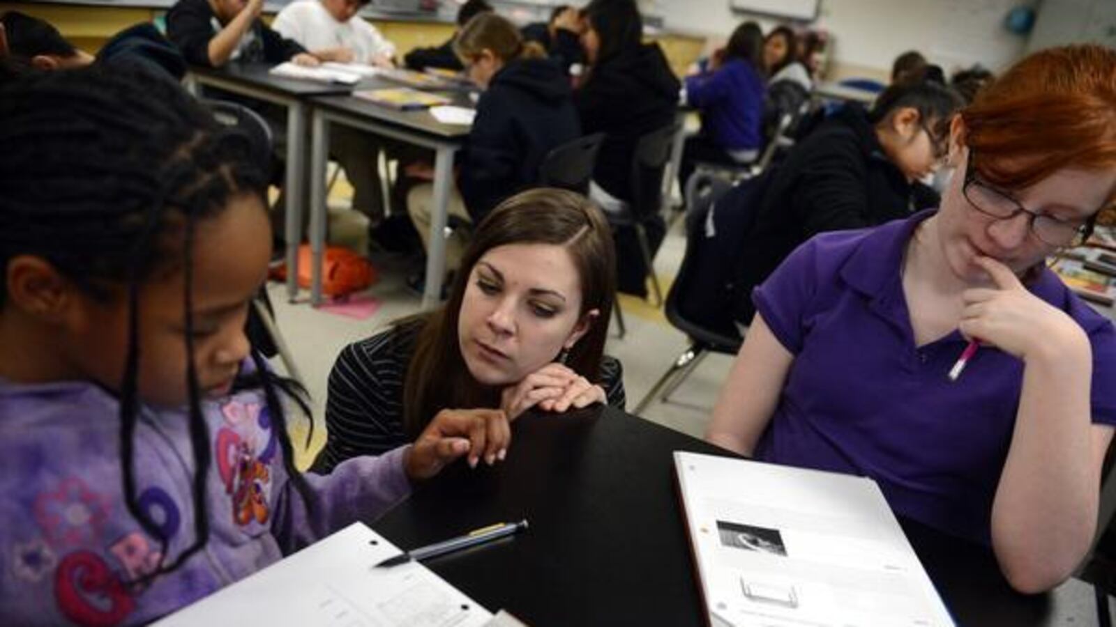 Sixth-grade science teacher Monica Wisniewski works with Pija Williams Terralee, left, and Myth Cubbison at Kearney Middle School in Commerce City. Kearney is in Adams County School District 14.