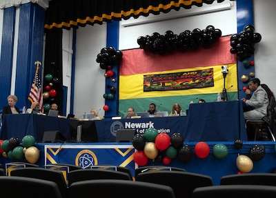 A photograph of adults sitting across a school auditorium.