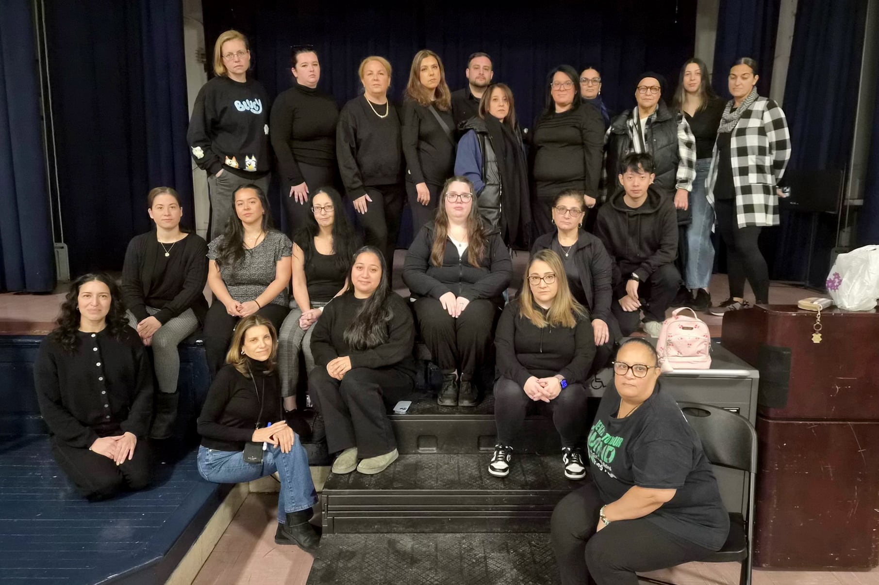 A photograph of a large group of adults posing for a portrait inside a large building.