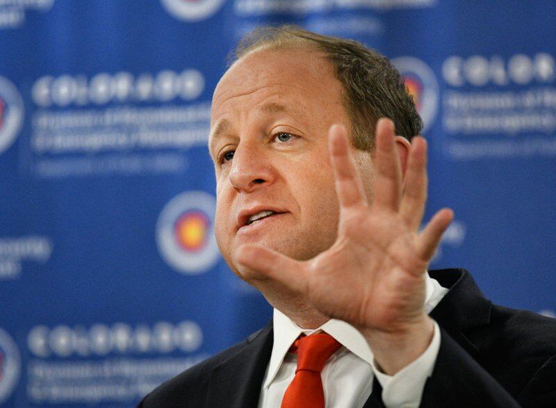 Governor Jared Polis gestures with his hand while speaking.
