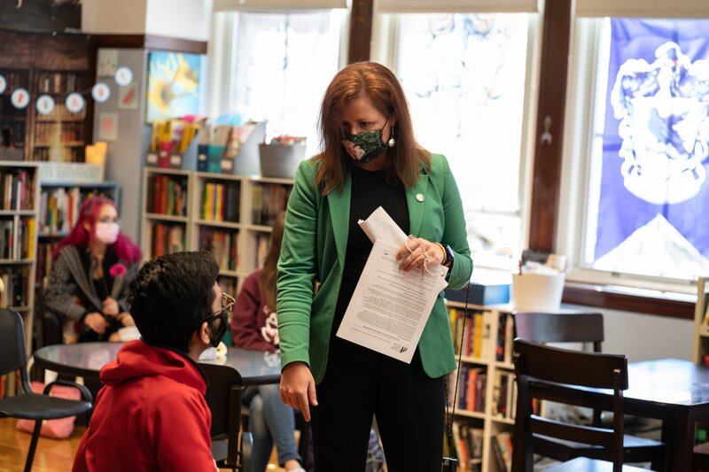 Senn High School Principal Mary Beck wears a bright green jacket and talks with student Muhammad Khan in English class on the first day back to classrooms for students on April 23, 2021.