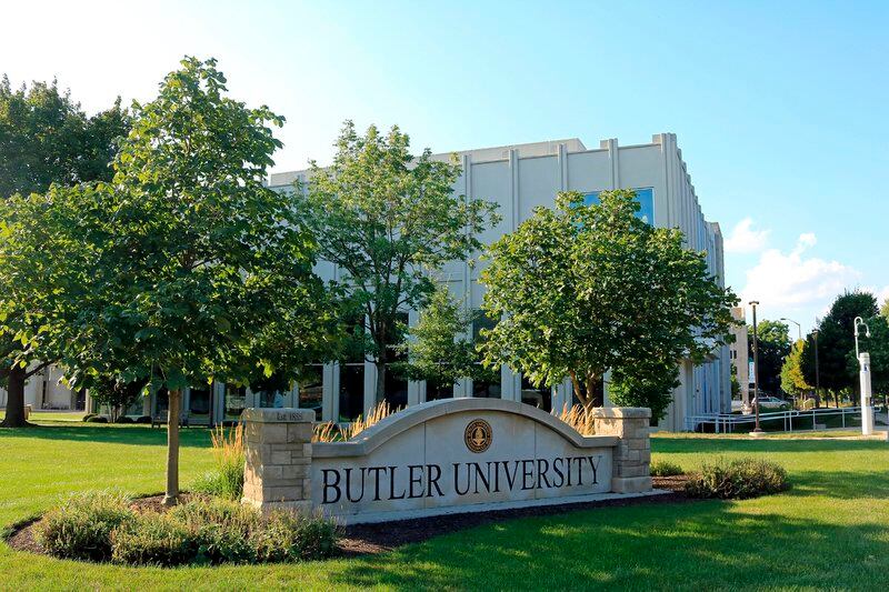 Outside sign that says Butler University with trees around it and building in the background